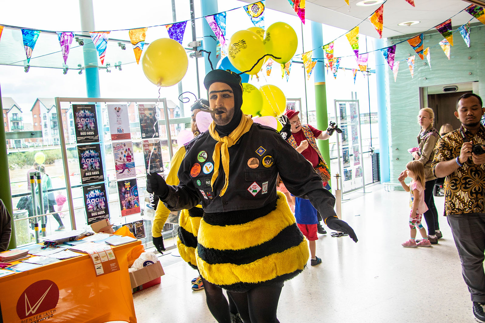 man dressed as a bee holding balloons
