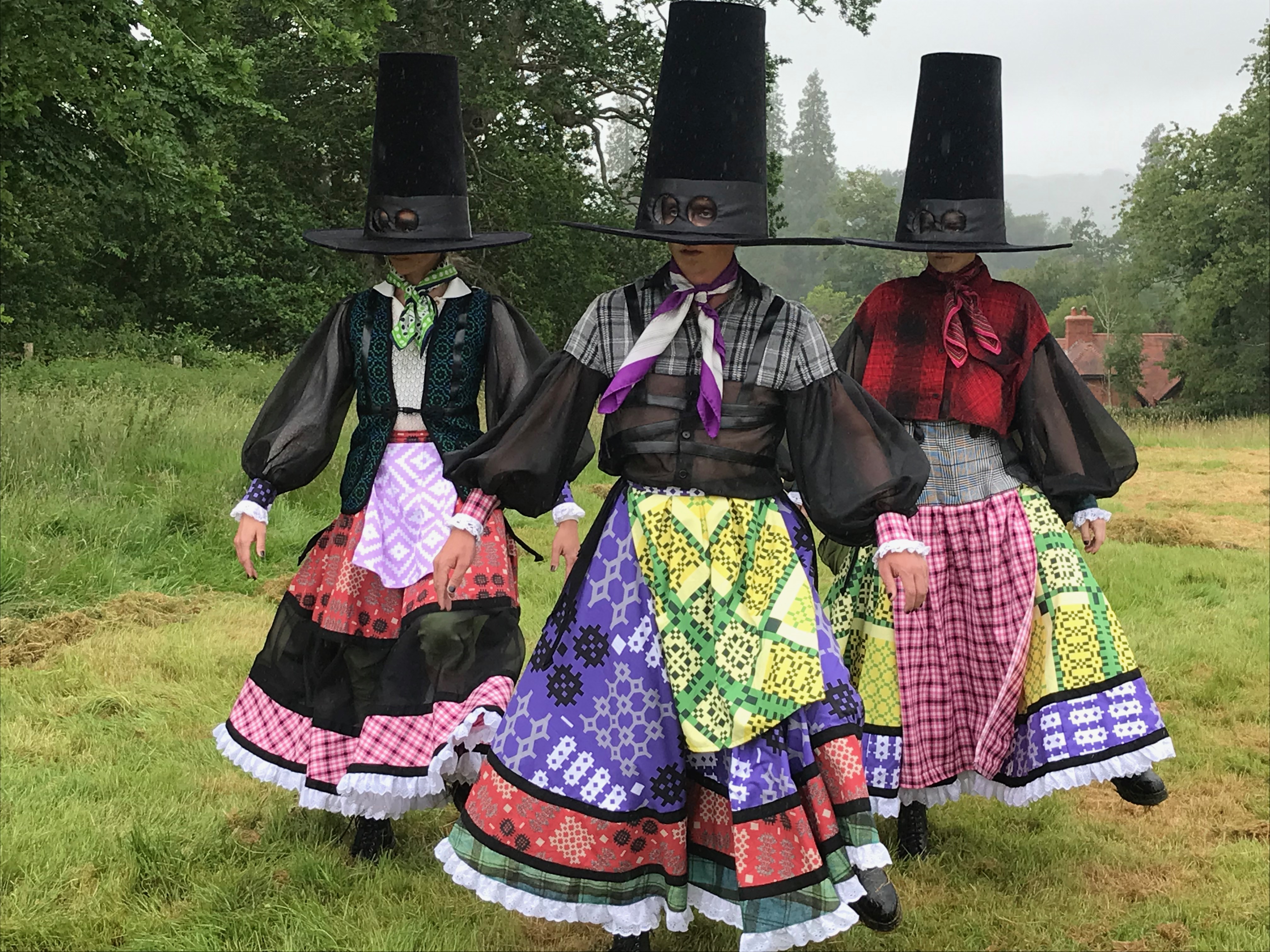 Three people in traditional Welsh costumes with tall hats