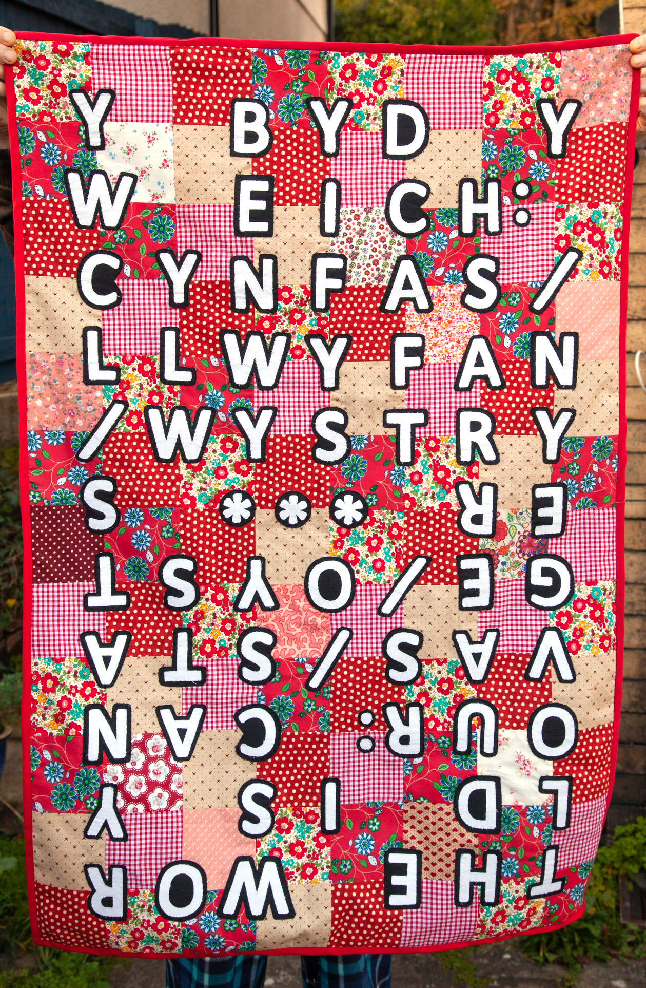 Red and pink quilt with bilingual writing on it.jpg