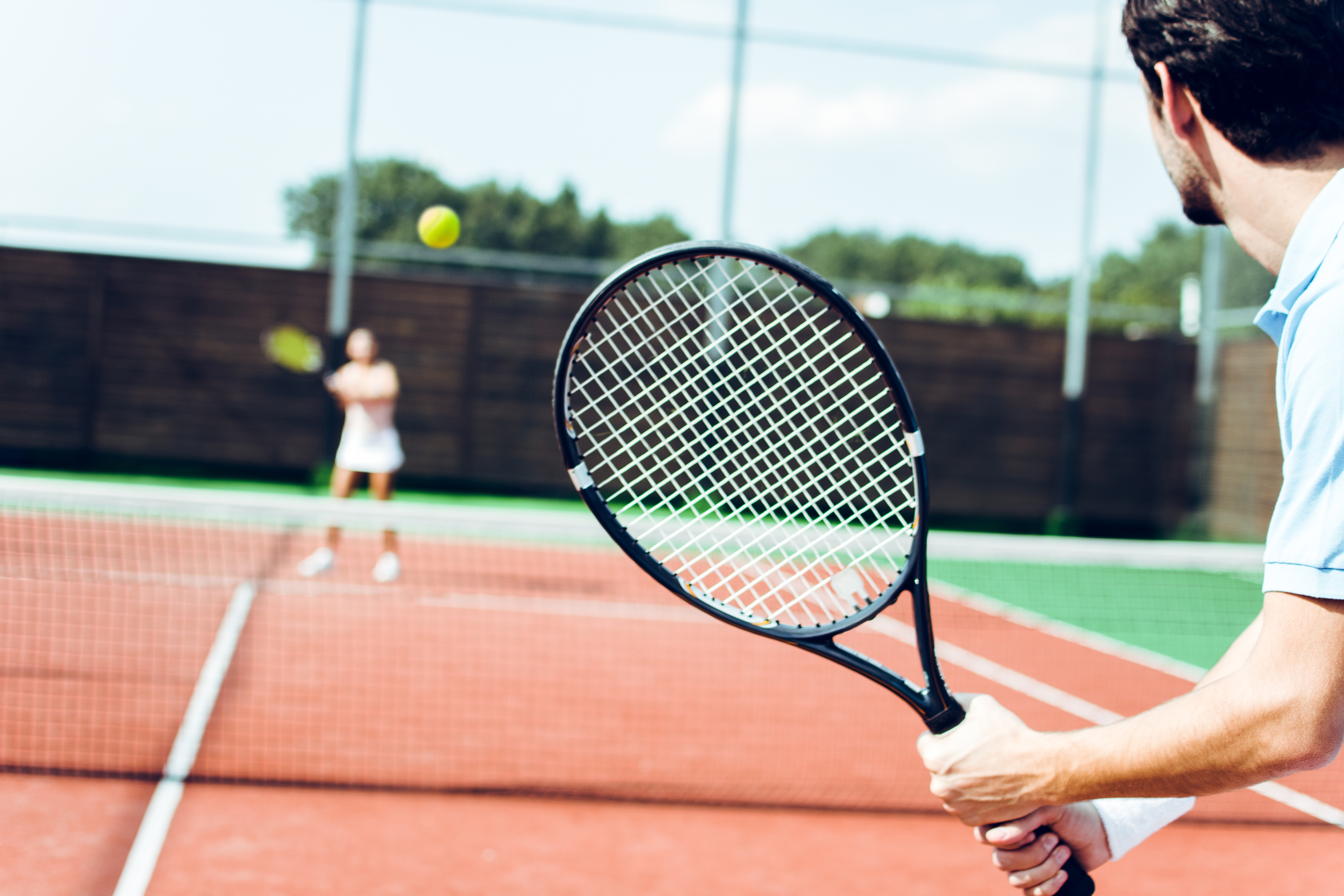Couple playing on an outdoor tennis court