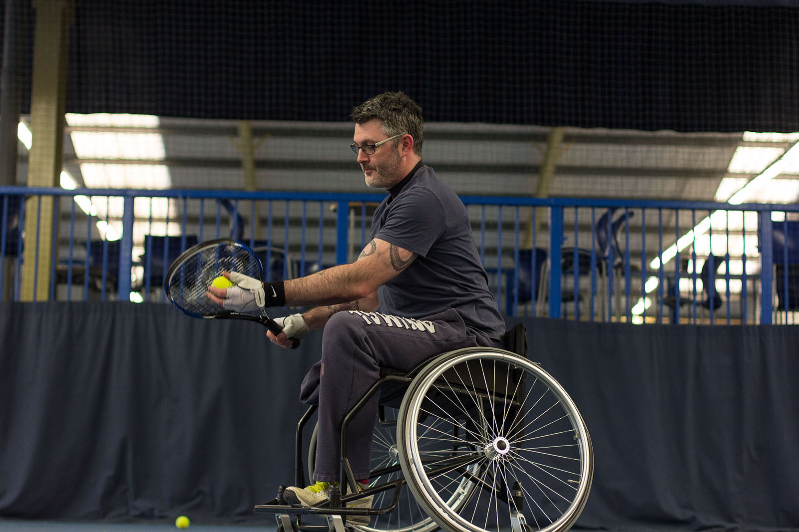 man in a wheelchair serving a tennis ball