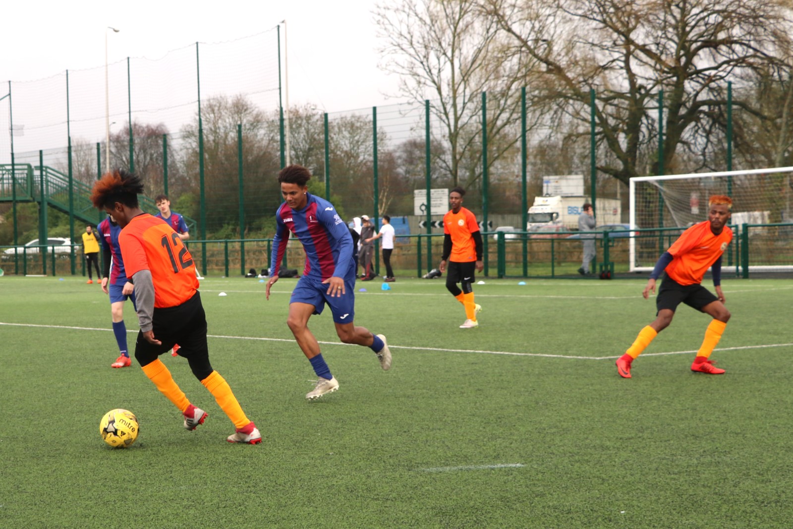 Men in orange football kit playing football.jpg