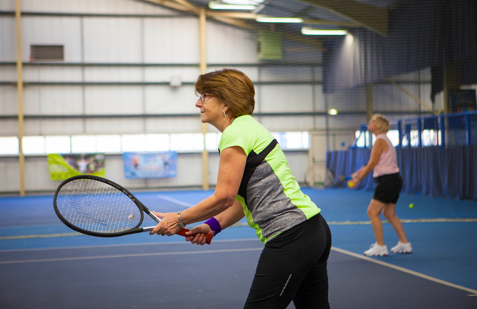 woman in a green t-shirt holding a tennis racket