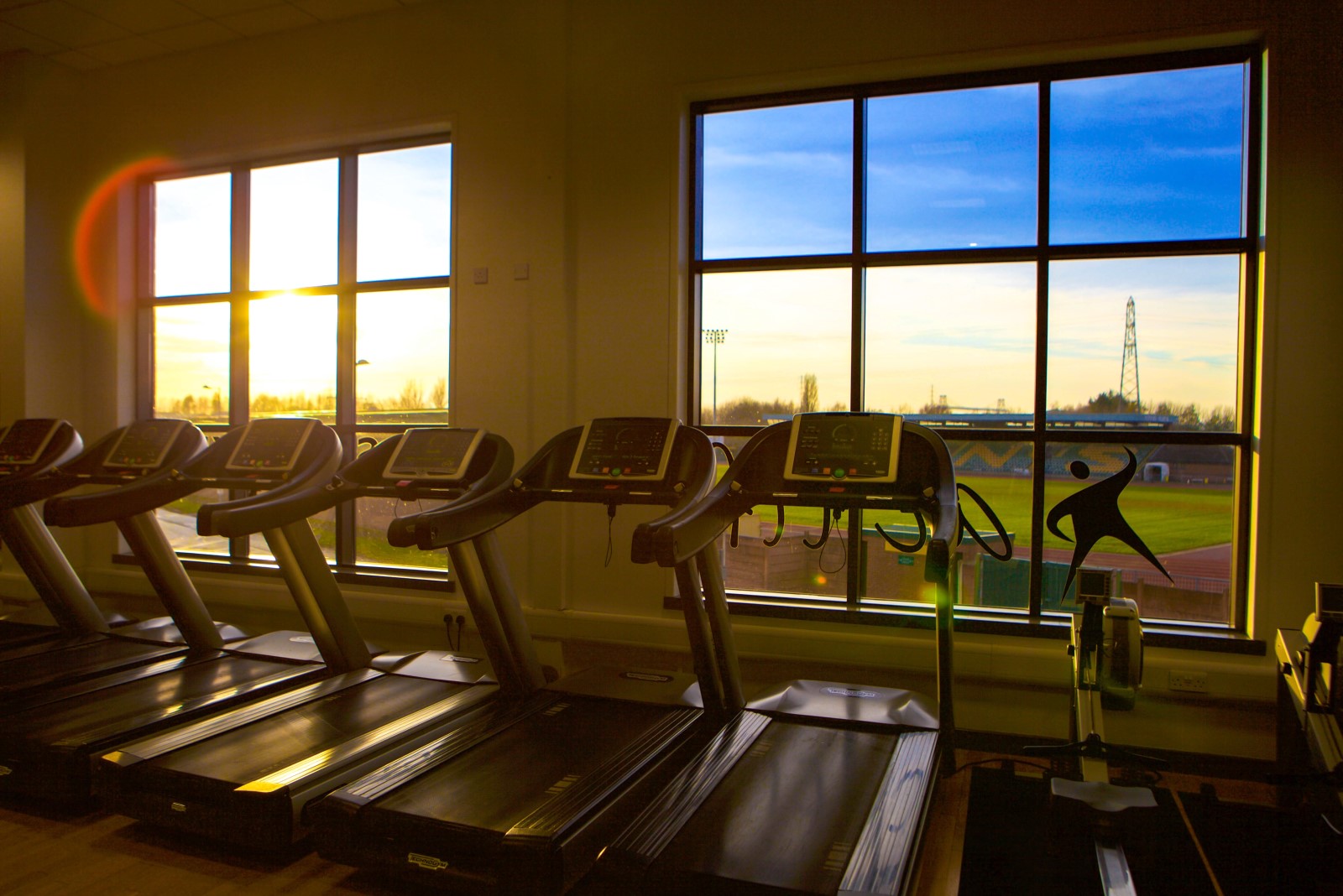 Line of tradmills with sun setting through gym window.jpg