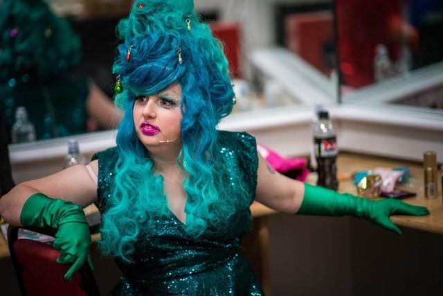 Drag queen dressed in turquoise sparkly outfit and turquoise wig