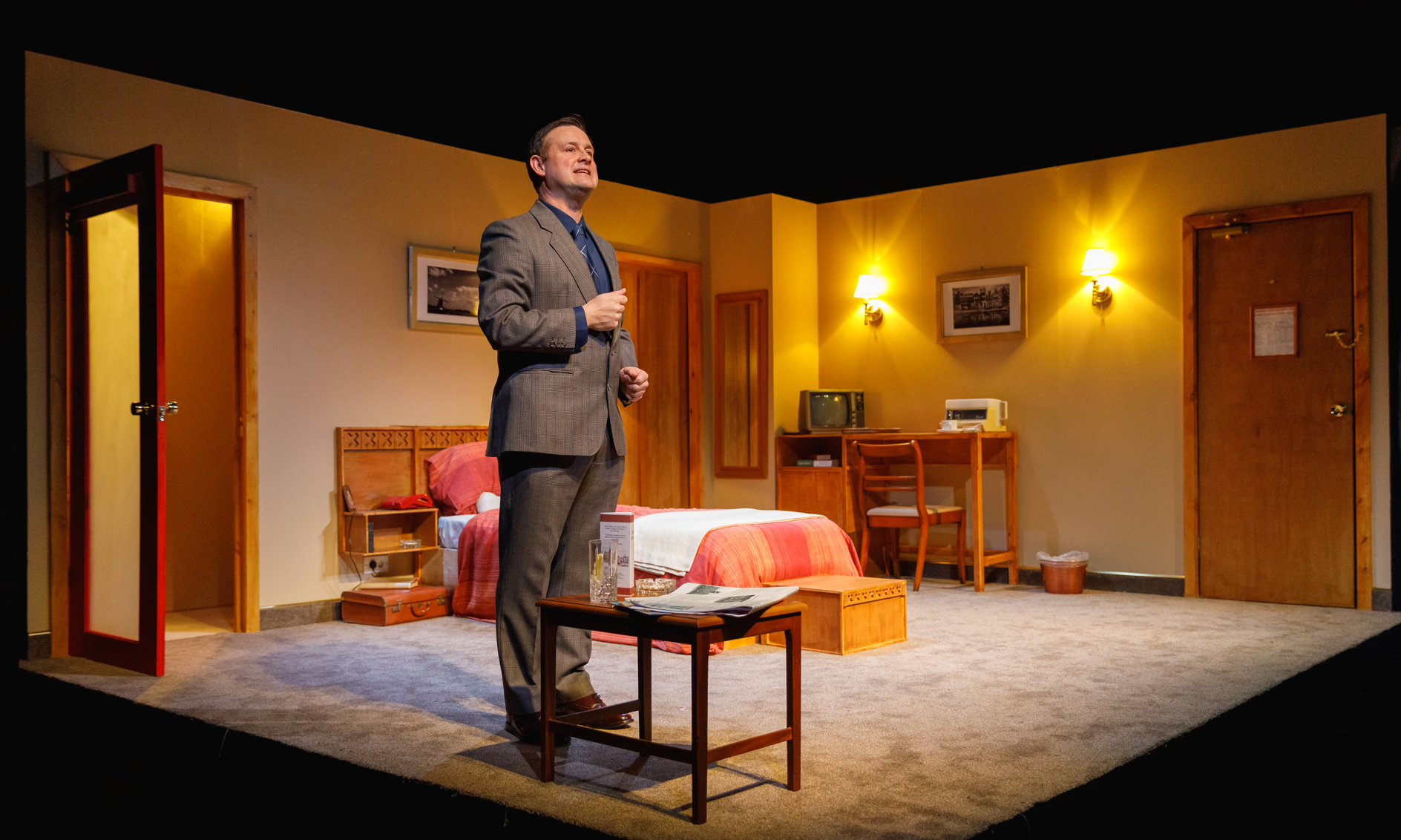 man in suit standing in hotel room set.PNG