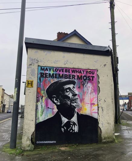 Portrait of a man with a colourful background with the wording May Love Be What You Remember Most installed on the side of a building.JPG