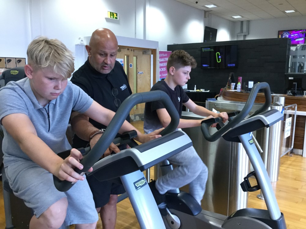 Newport Live instructor talking to two young boys on fitness bikes Newport Live instructor talking to two young boys on fitness bikes