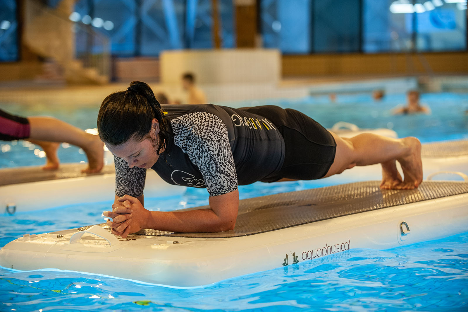 woman performing a plank on a float in an aqua exercise class