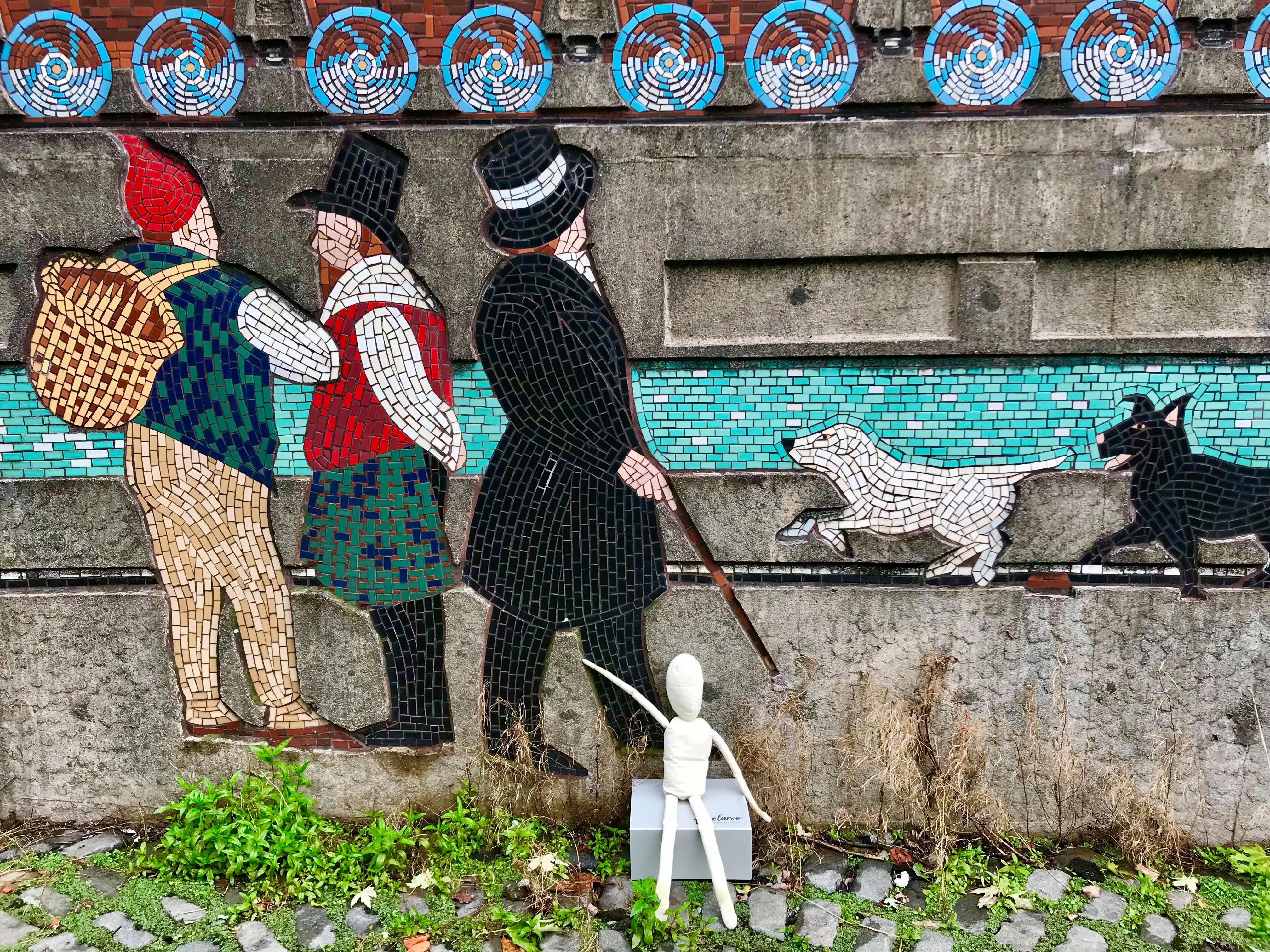 Cloth puppet sitting in front of a Chartist mural