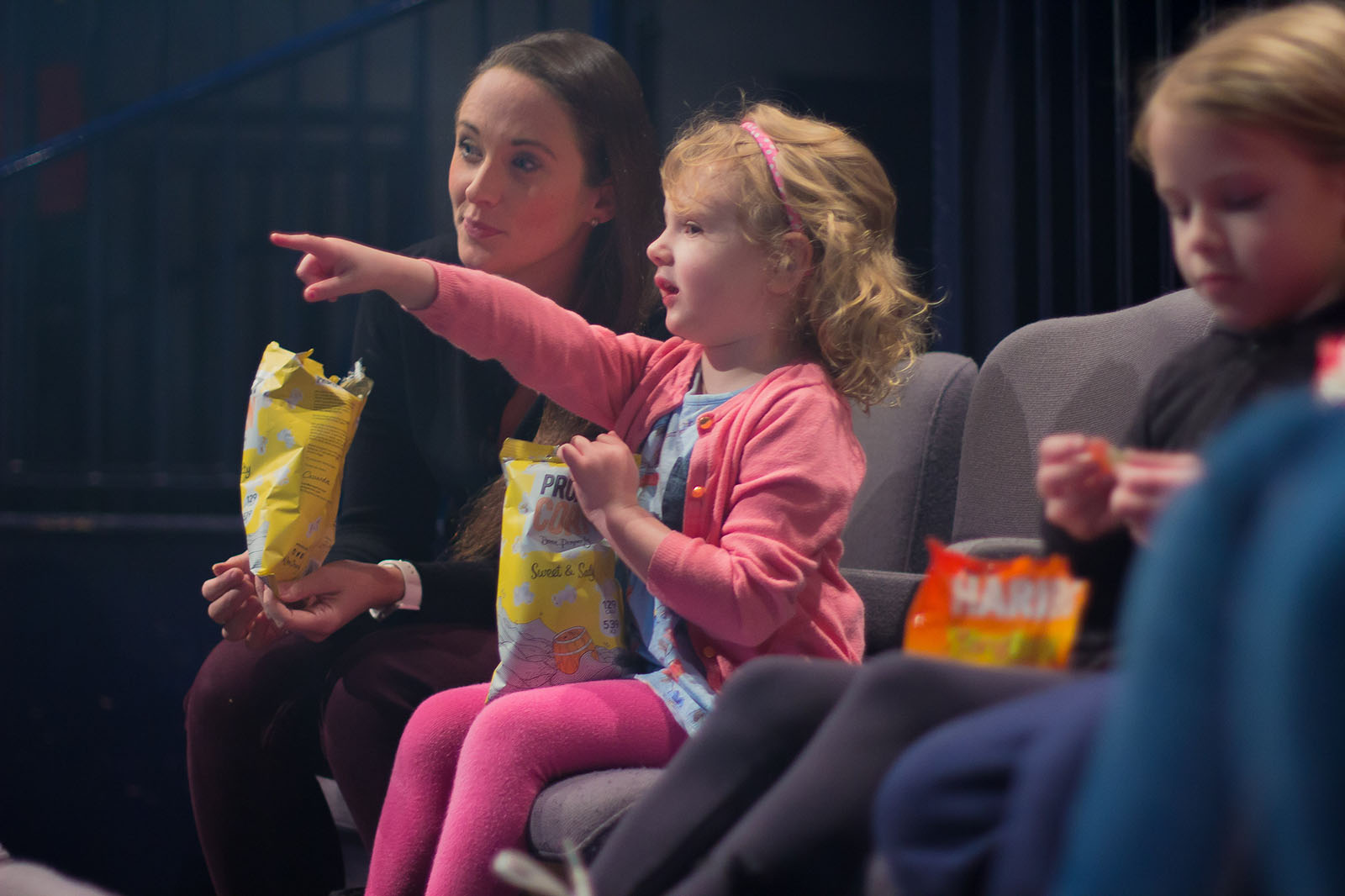 young girl pointing at a cinema screen holding popcorn