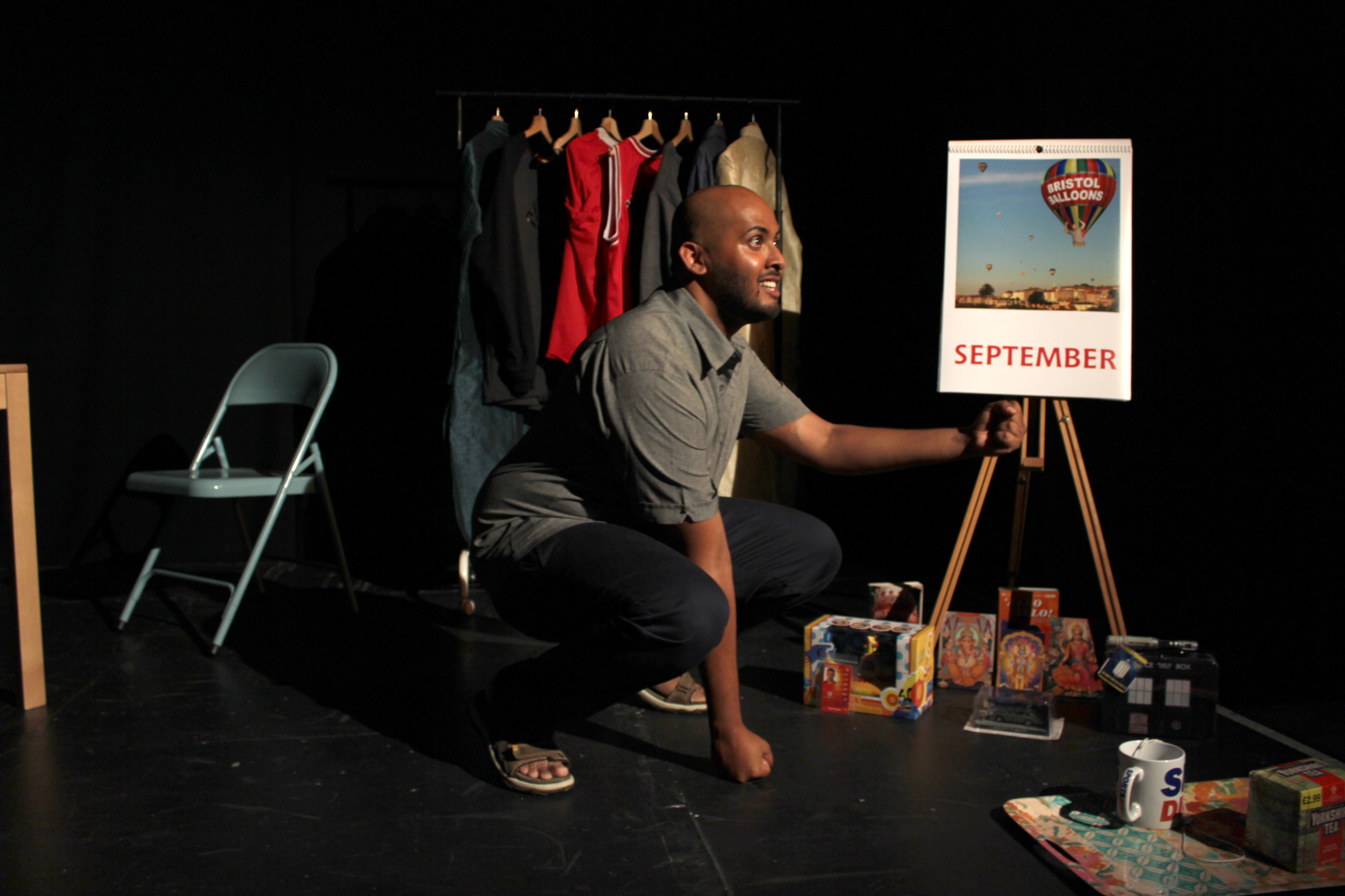 Man crouching next to a calendar on an easel
