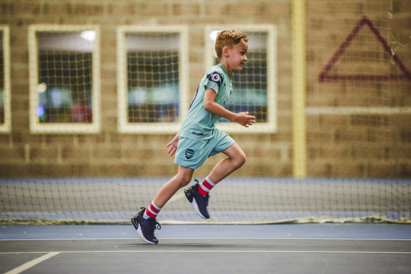 boy in a football kit running in a sports hall.jpg