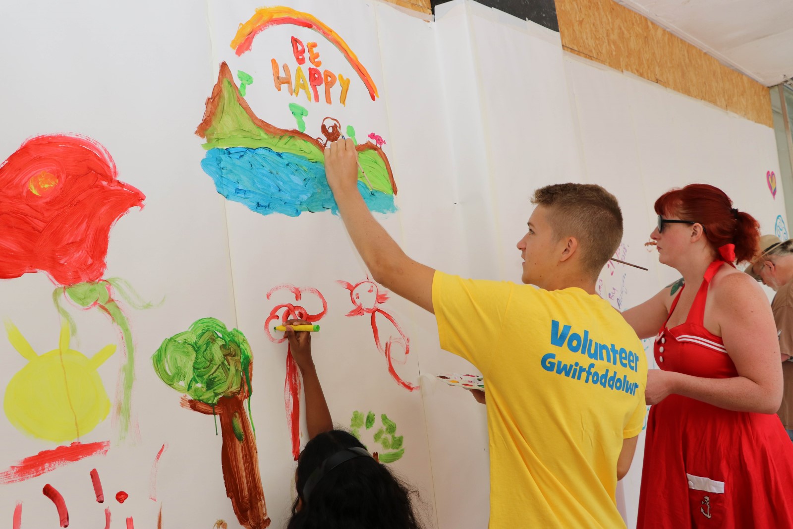 Man in volunteer t-shirt painting pictures on a wall.jpg