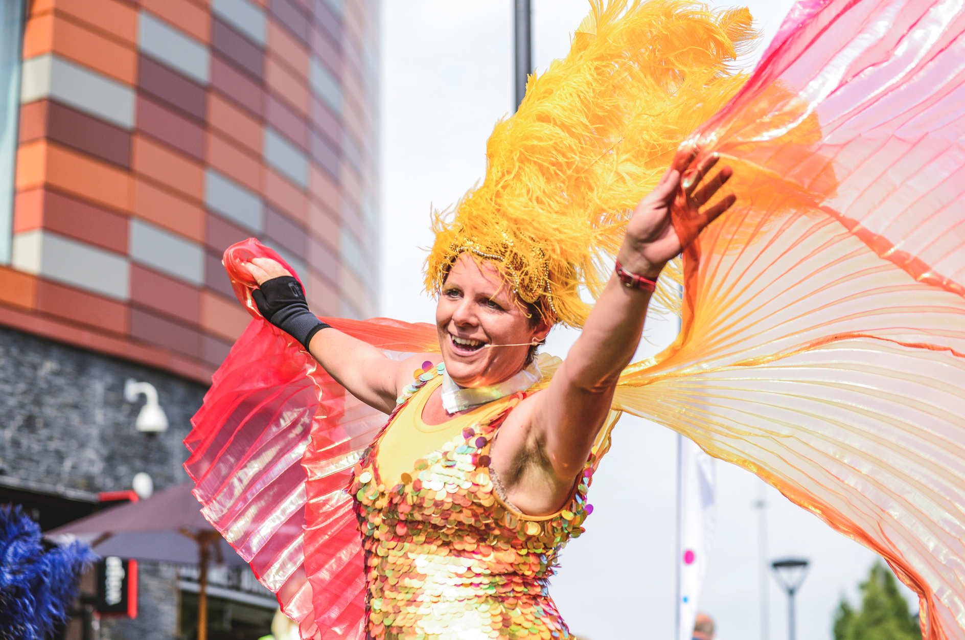 Lady in orange sequin outfit with yellow feathered  headress