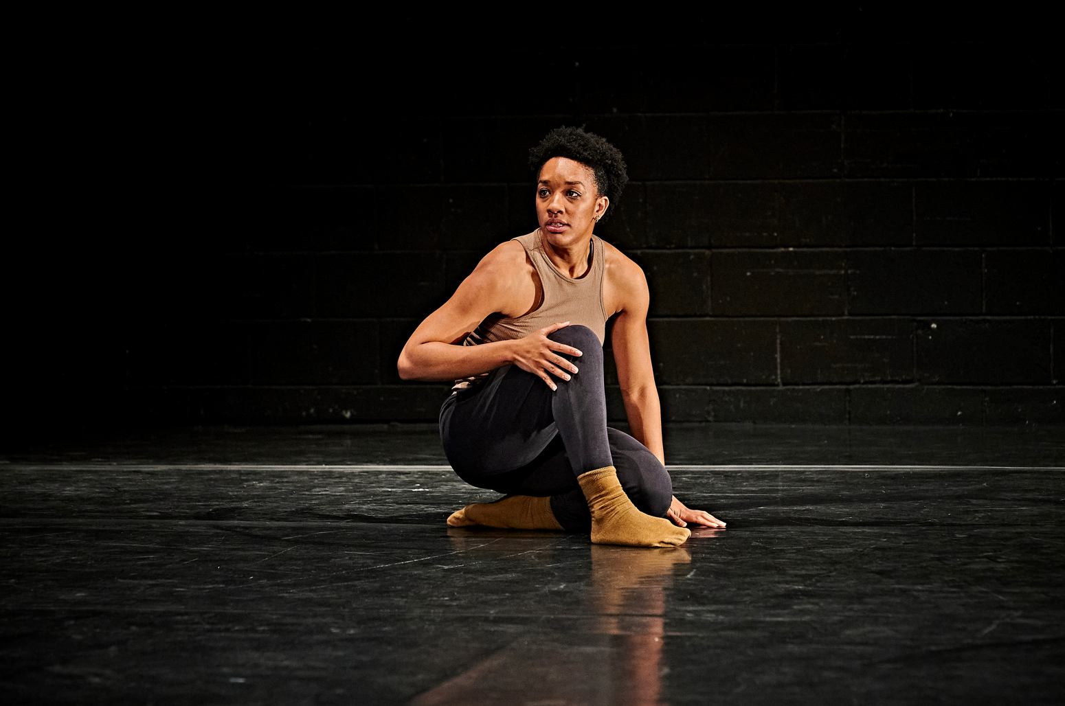 Performer Krystal S Lowe crouching on The Riverfront's stage