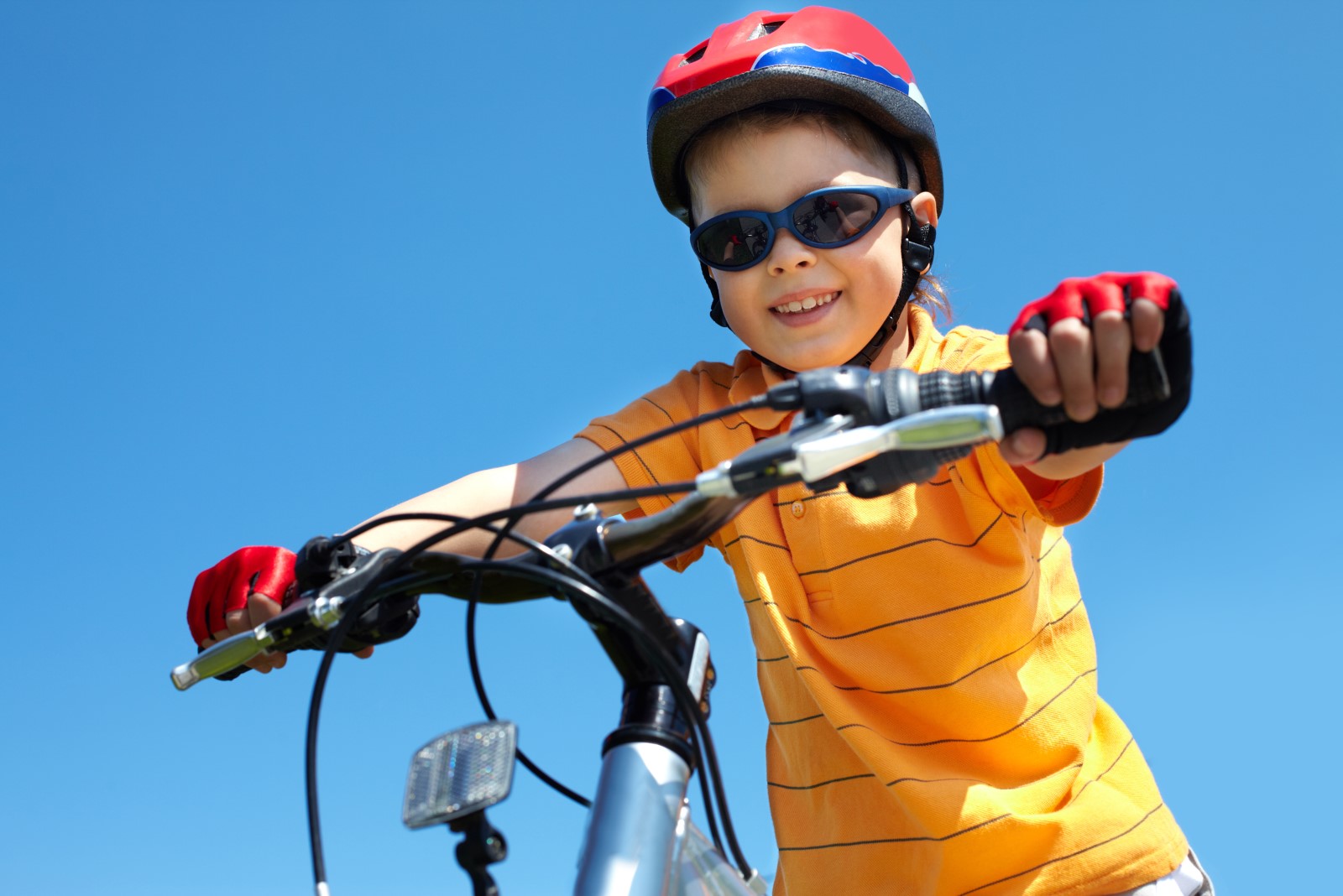 boy in red helmet holding bicycle handlebars