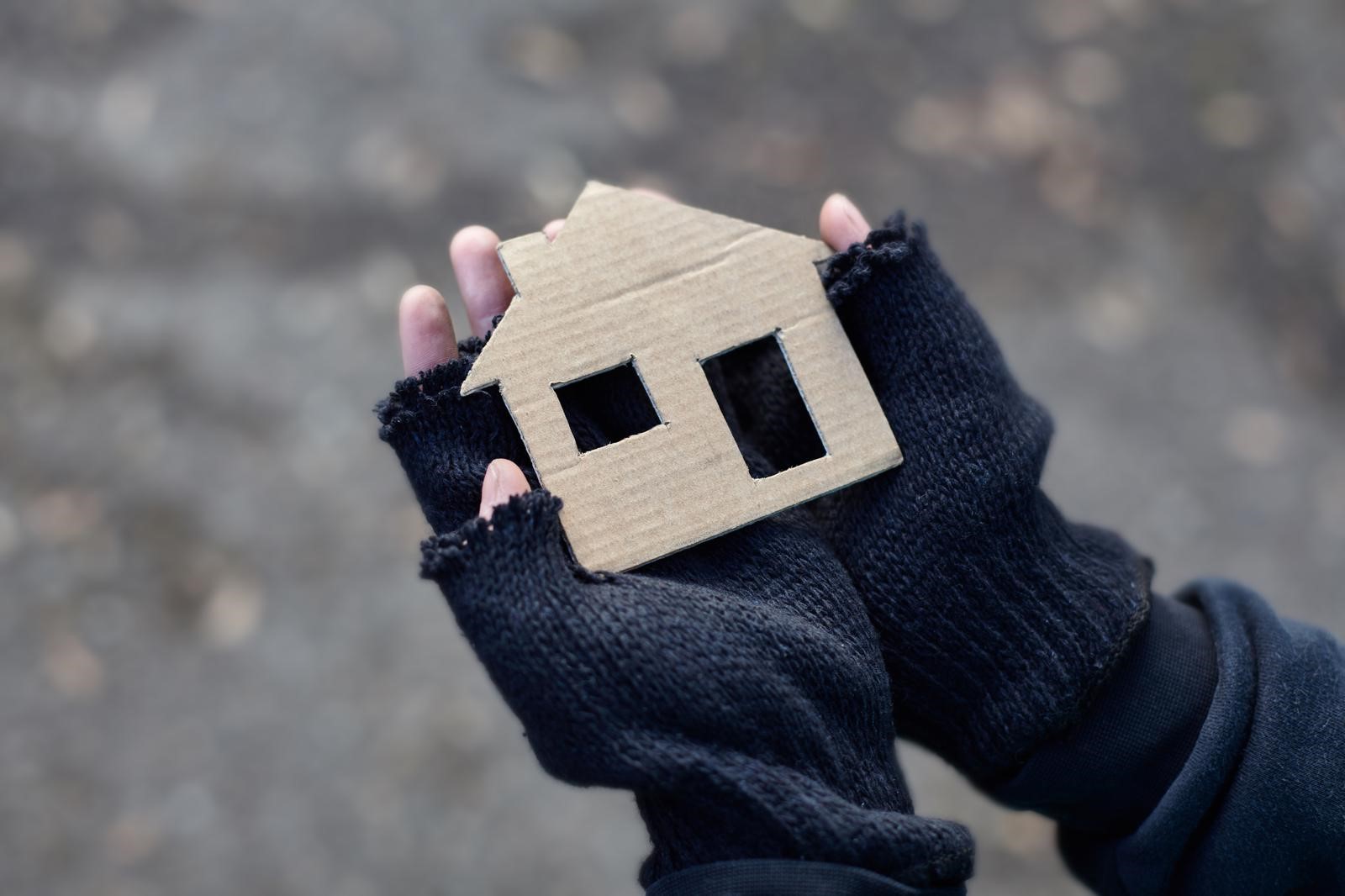 Gloved hands holding cardboard house